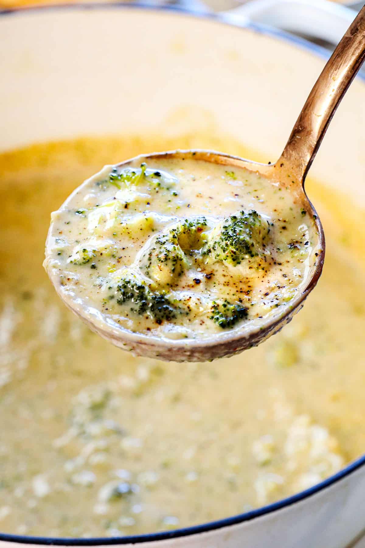 up close of a ladle full of recipe for broccoli cheese soup showing the rich, velvety creaminess