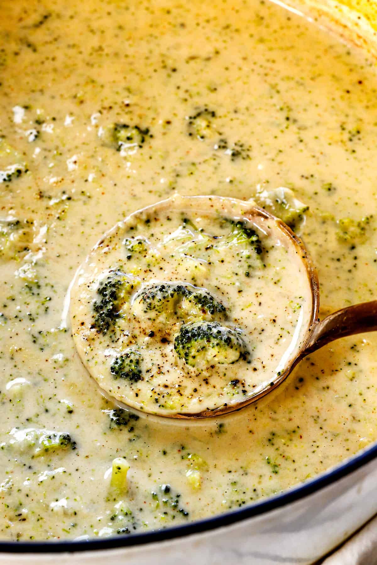 a ladle of broccoli cheese soup recipe showing how creamy it is