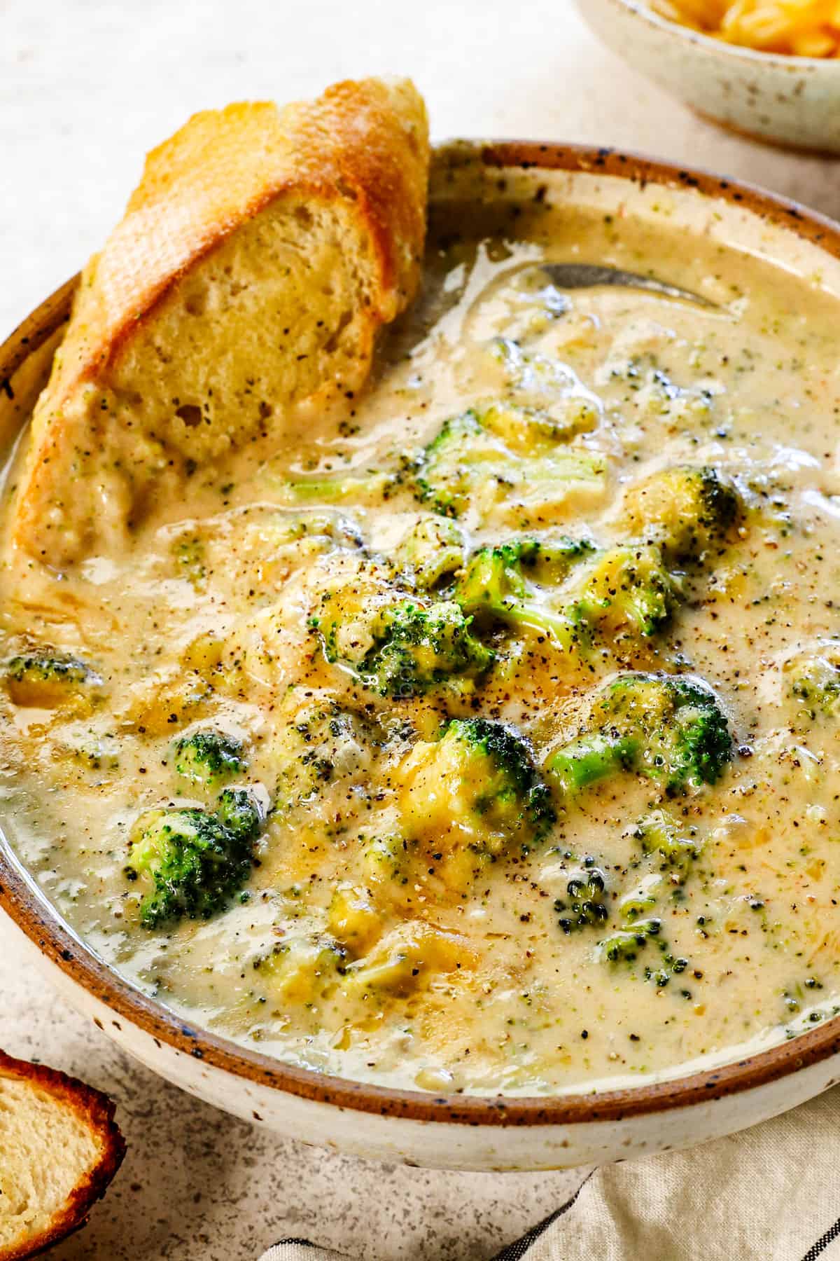 side view of a bowl of broccoli cheese soup recipe showing how to serve it with cheese ganrish