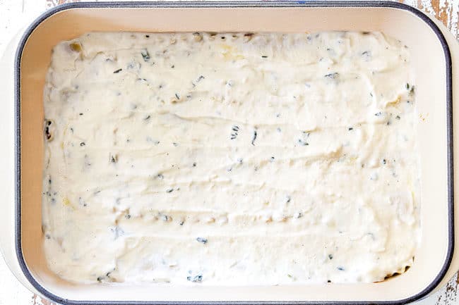 showing how to layer lasagna with a layer of ricotta cheese