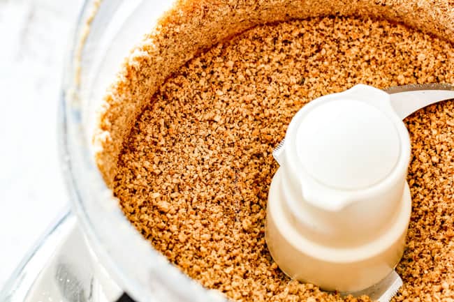 showing how to make pecan pie cheesecake with graham cracker by crushing graham crackers in a food processor