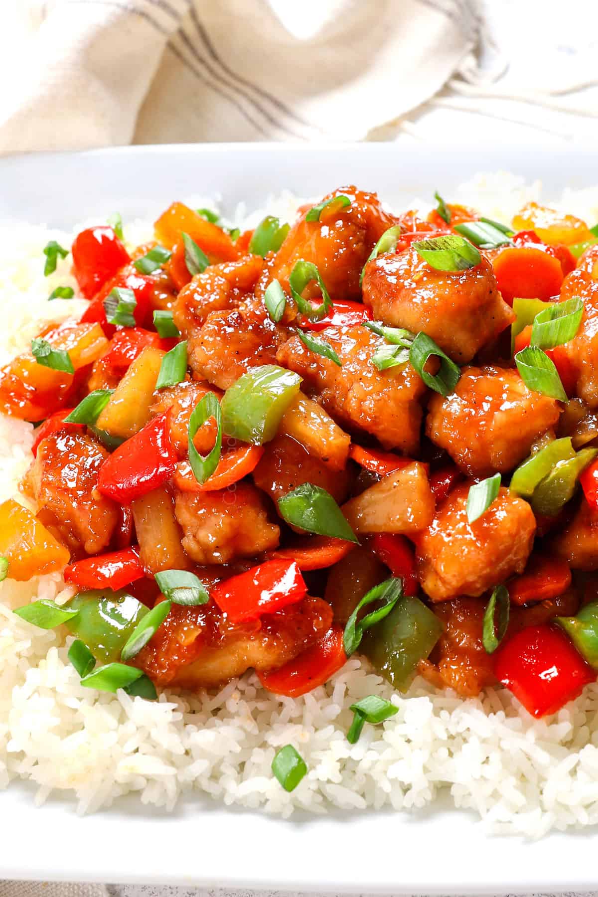 sweet and sour chicken served over rice garnished with green onions