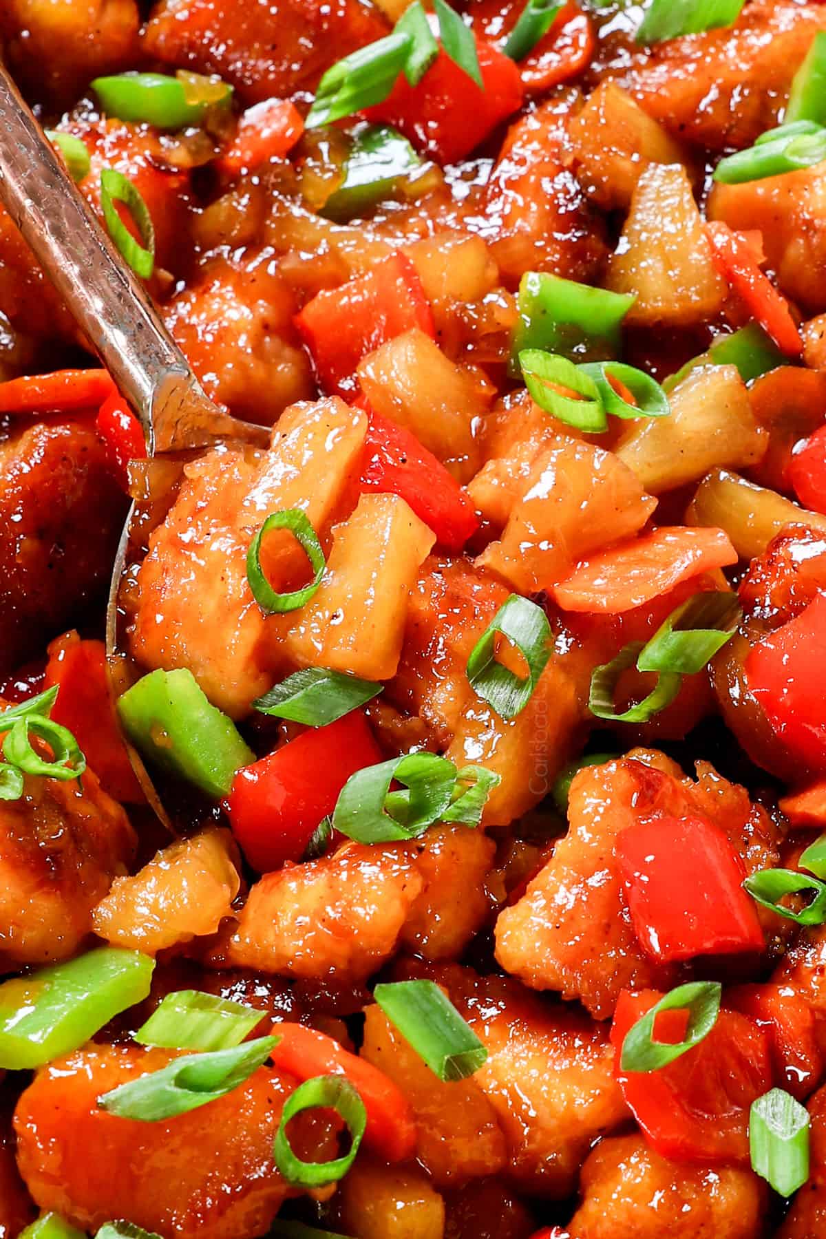 showing how to make sweet and sour chicken by stirring the chicken, vegetables and pineapple together after baking