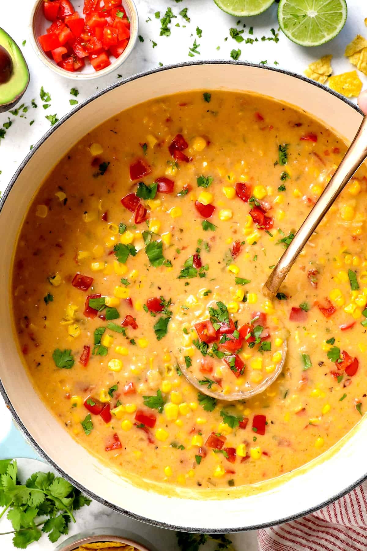 showing how to serve chicken corn soup recipe by topping it with tomatoes and cilantro