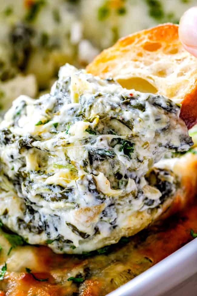 up close of piece of bread with spinach artichoke dip on it