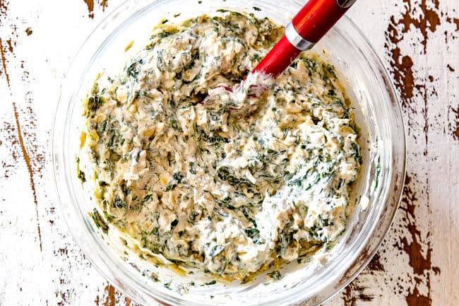 showing how to make spinach artichoke dip recipe by mixing all the ingredients together in a glass bowl