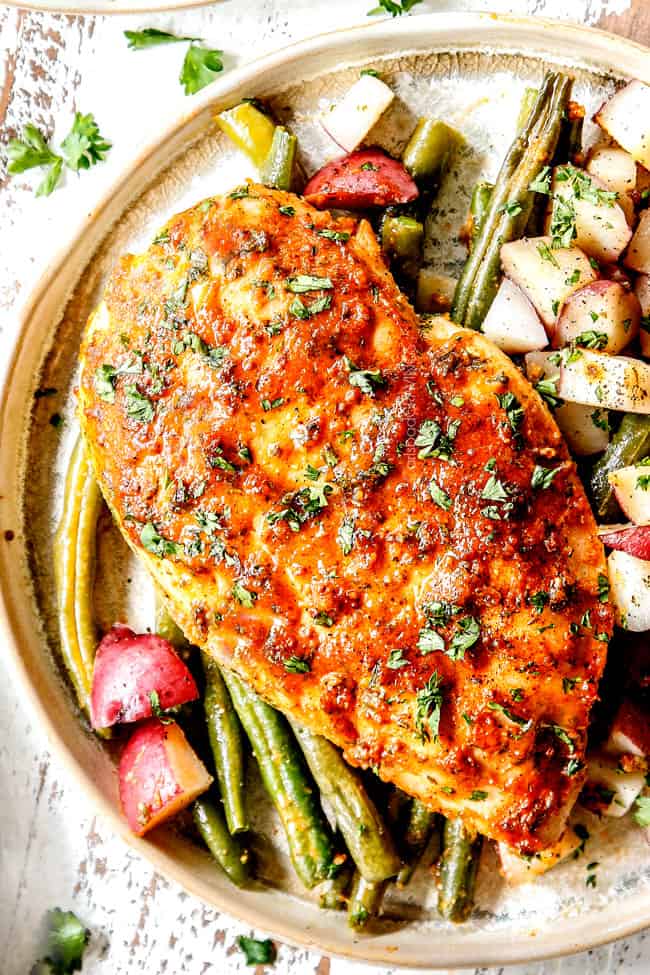 up close of a plate of baked honey mustard chicken laying on potatoes and green beans