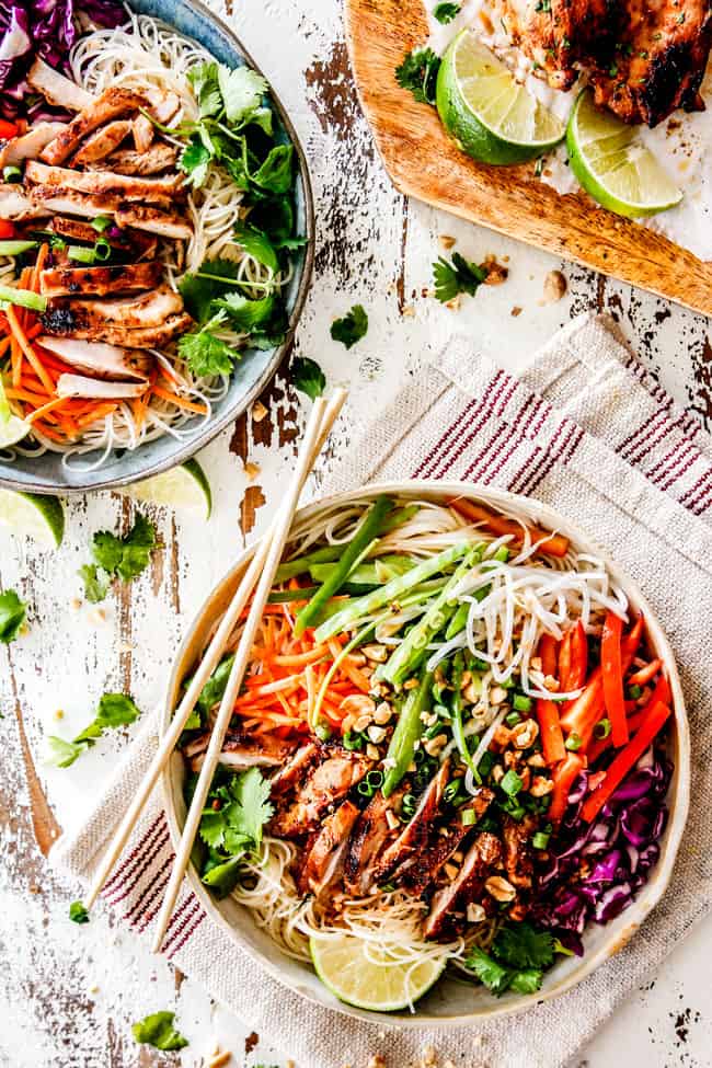 top view of two Vietnamese noodle bowls with rice noodles, lemongrass chicken, shredded carrots, julienned carrots, bean sprouts and snow peas