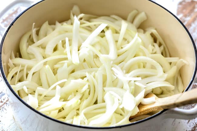 showing how to caramelize onions for French Onion Soup by adding onions to a large white pot
