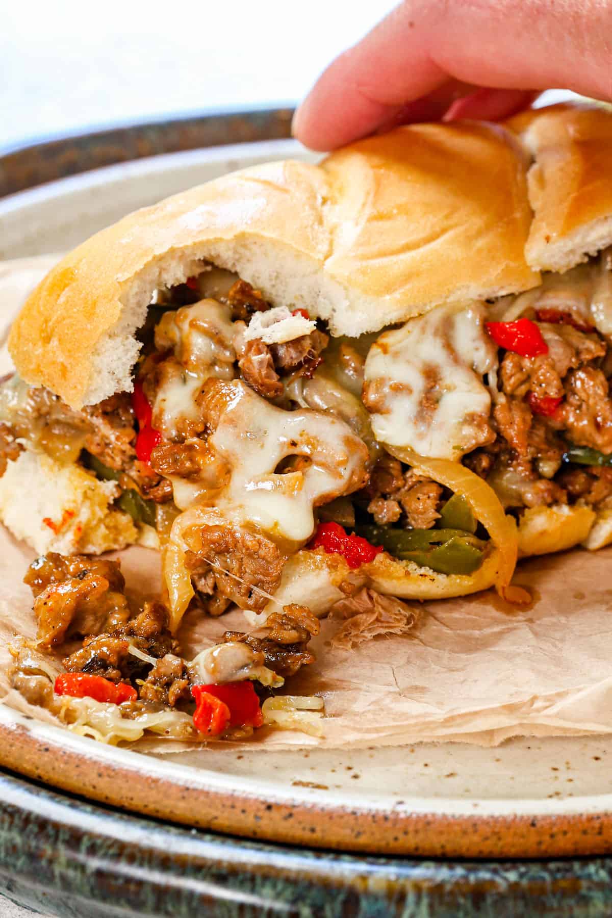 up close of Philly Cheesesteak sandwich with a bite taken out and cheese spilling out