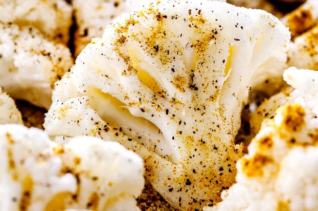 showing how to make roasted cauliflower by seasoning cauliflower and tossing with spices