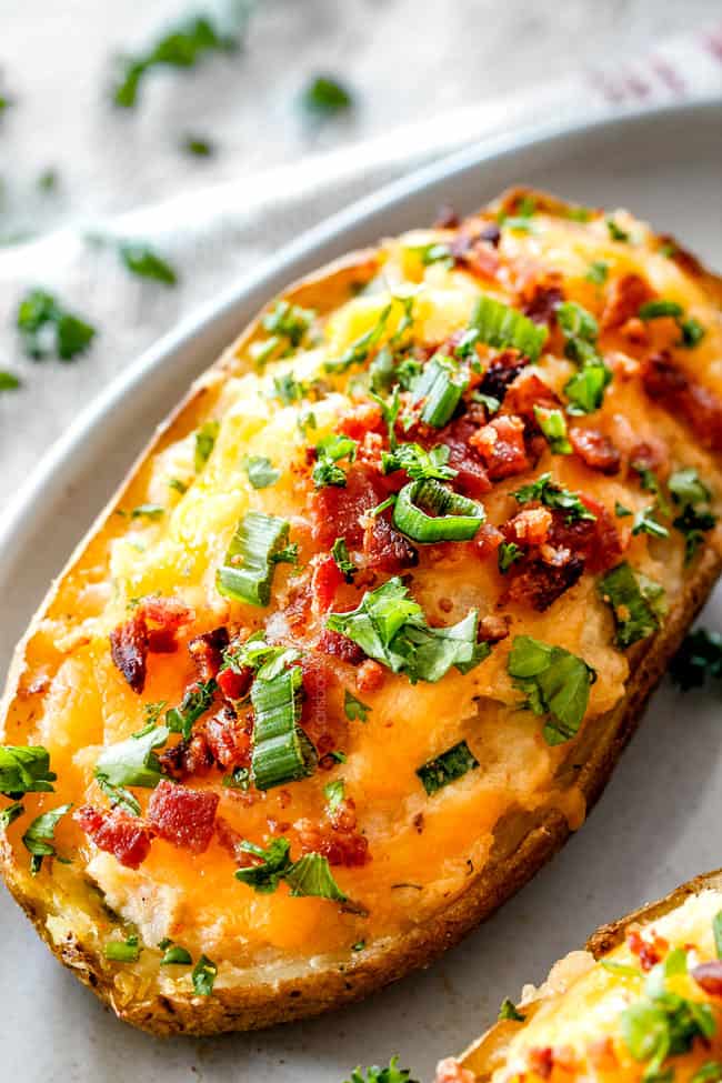 twice baked potatoes on a white plate with green onions and bacon
