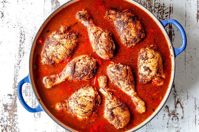 showing how to make Arroz con Pollo by adding chicken thighs and chicken drumsticks on top of rice