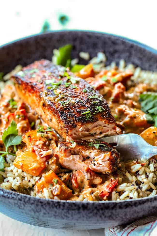 far away iew of pan seared blackned salmon on rice in black bowl with sauce