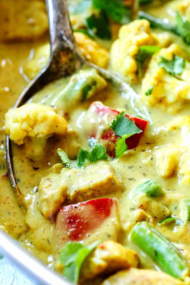 up close of a spoonful of creamy coconut curry chicken with vegetables