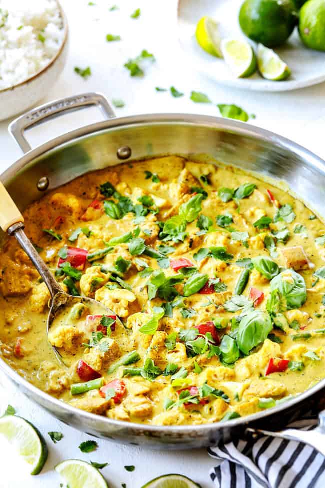 far away view of a stainless steak skillet of creamy coconut curry chicken recipe garnished with cilantro and lime