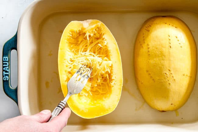 showing how to cook spaghetti squash halves in the microwave by shredding the squash with a fork