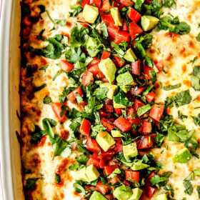 top view of enchiladas verdes casserole topped with cheese, cilantro, tomatoes, avocados