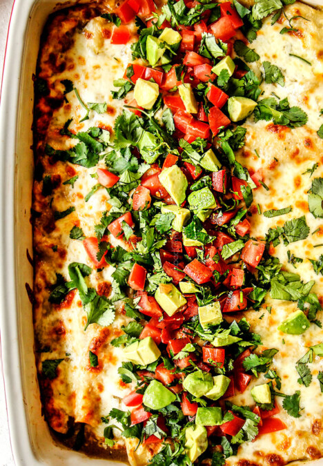 top view of enchiladas verdes casserole topped with cheese, cilantro, tomatoes, avocados