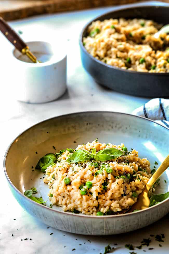 far away side view of easy spinach risotto recipe on a grey plate with a gold fork