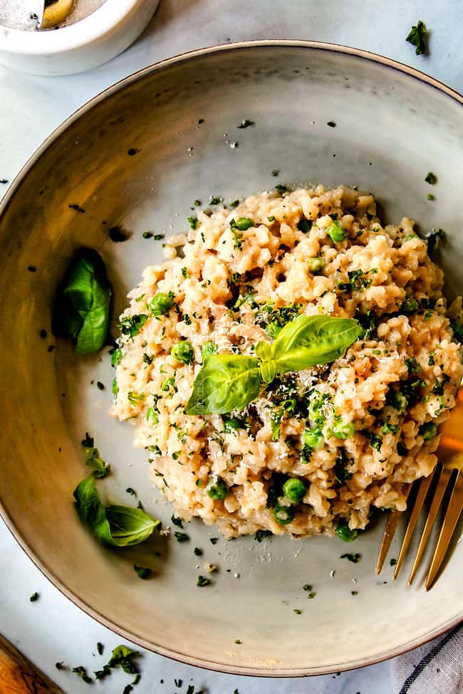 top view of spinach risotto recipe in a grey dish garnished with basil