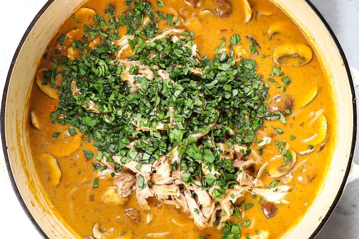 showing how to make Thai chicken soup by added shredded chicken, cilantro and lime juice