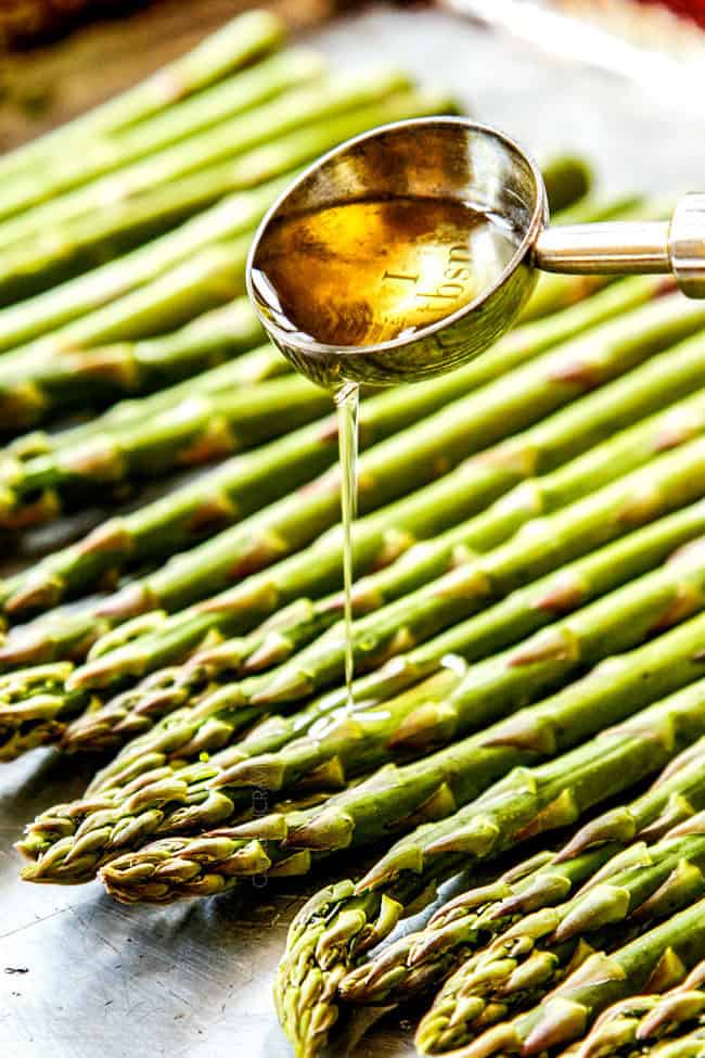 showing how to cook asparagus by drizzling with olive oil