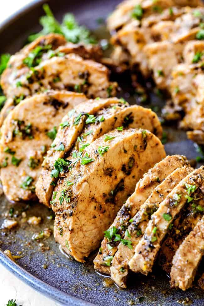 up close of sliced oven baked pork tenderloin recipe with garlic butter herbs