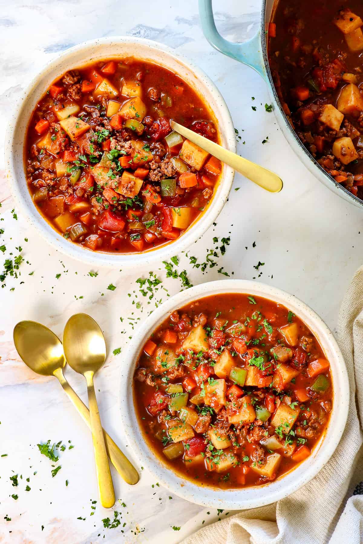 two bowls of hamburger soup topped with cheese