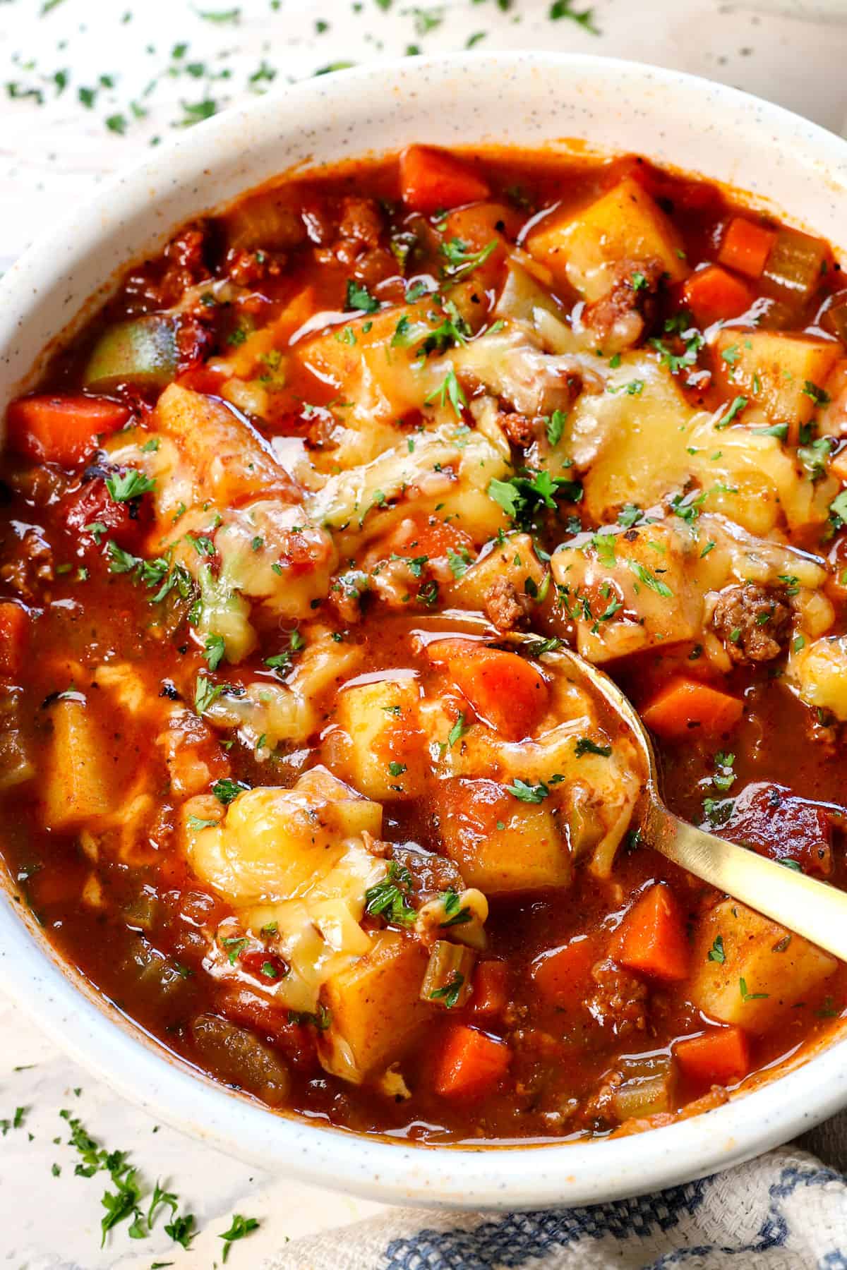 showing how to serve hamburger soup by adding cheese to melt