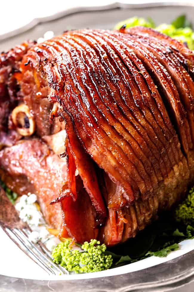 up close of a a juicy honey glazed ham on a white platter