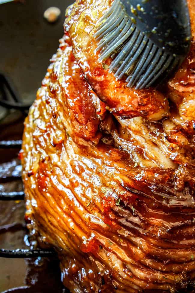 showing how to make honey baked ham by glazing ham on a roasting rack with honey glaze