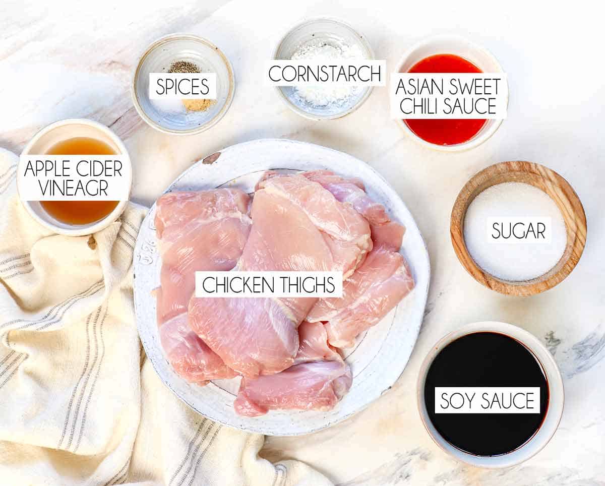 top view of teriyaki chicken recipe ingredients: chicken thighs, soy sauce, sugar, apple cider vinegar, Asian sweet chili sauce, cornstarch, ground ginger, ground garlic, pepper