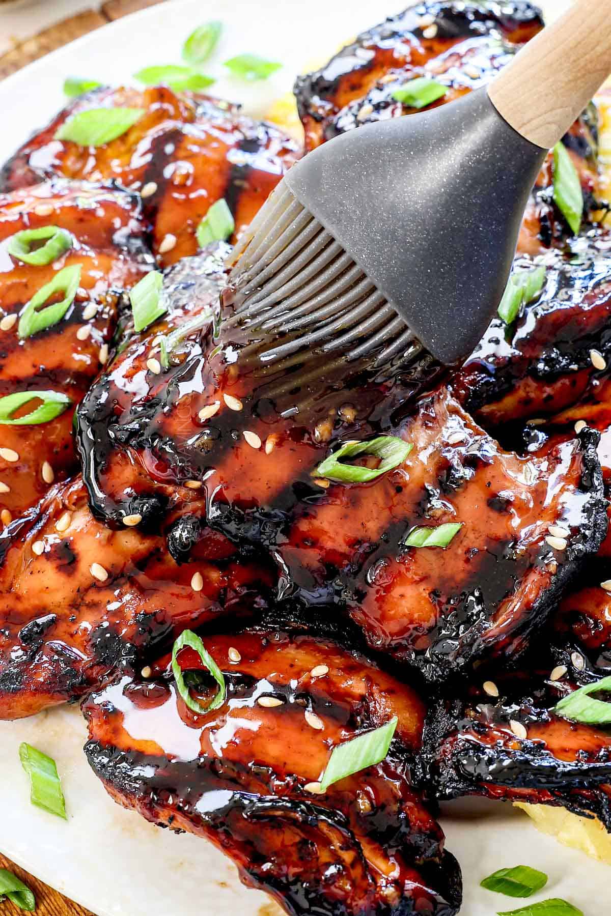 showing how to make teriyaki chicken by brushing the grilled chicken with teriyaki sauce