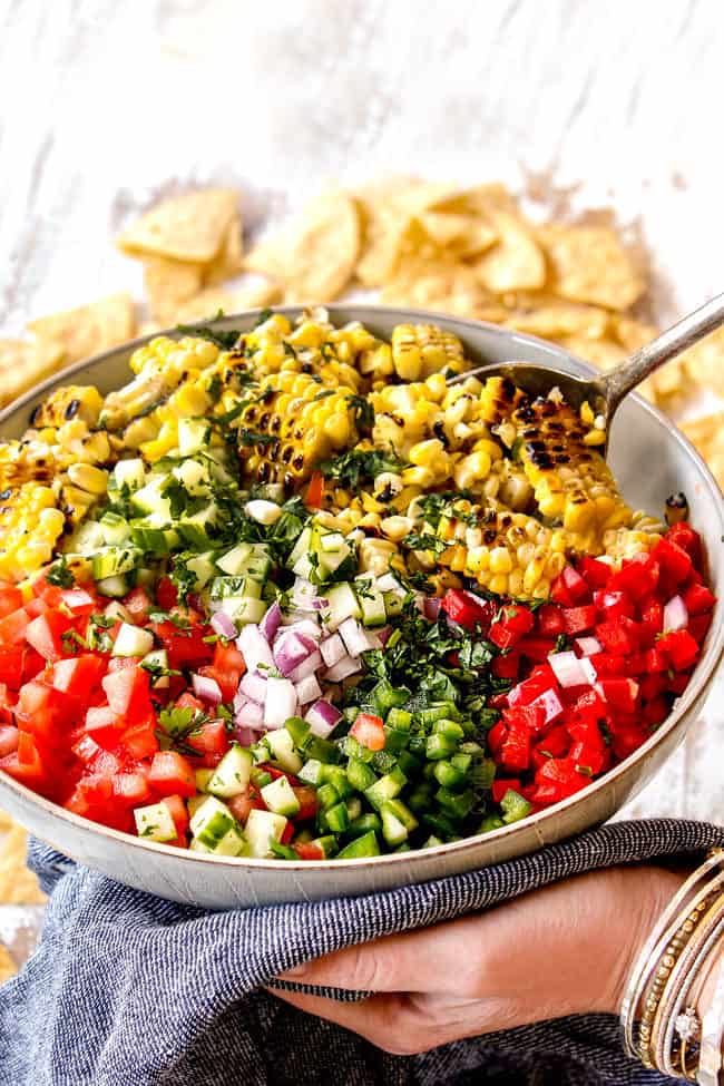 showing how to make pork taco topping by adding corn salsa ingredients to a bowl