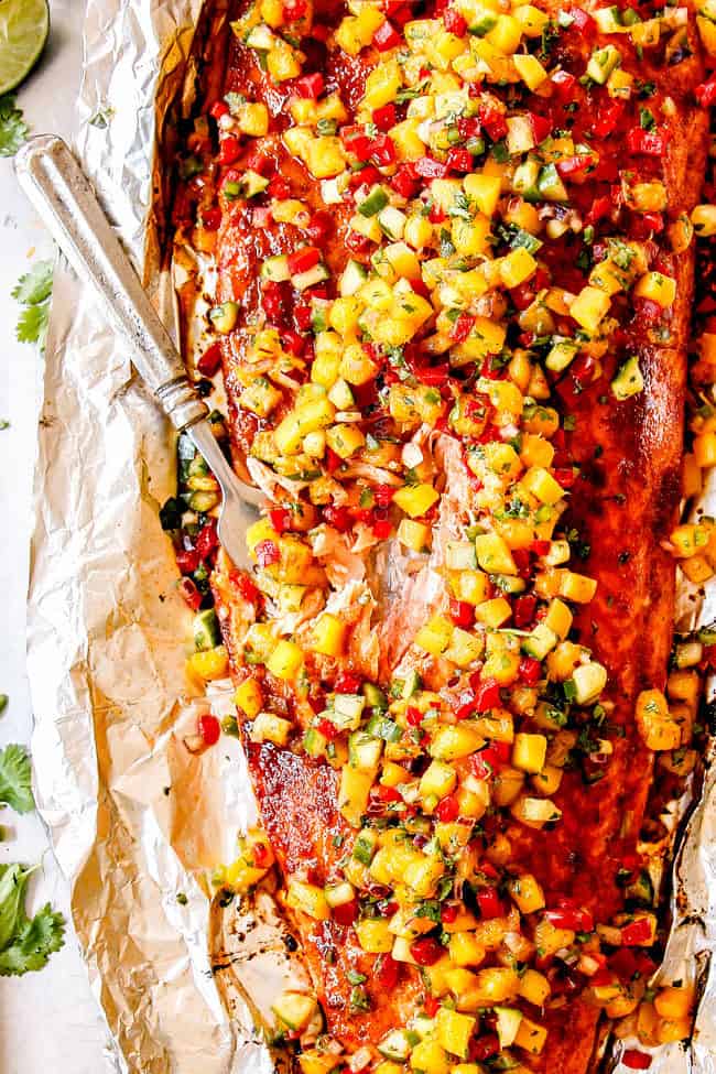 bovenaanzicht van een vork die gezonde zalm eet in folie met mango salsa