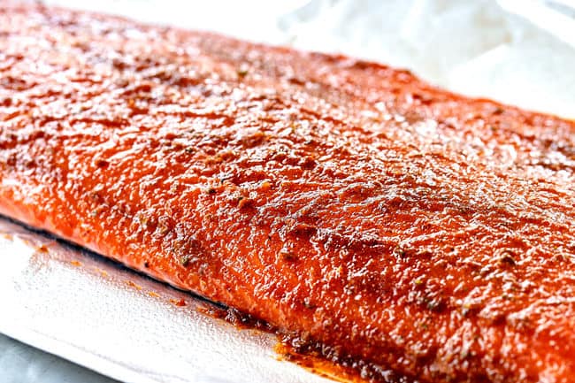 vista laterale che mostra come fare il salmone con salsa di mango strofinando il salmone dappertutto con strofinamento umido