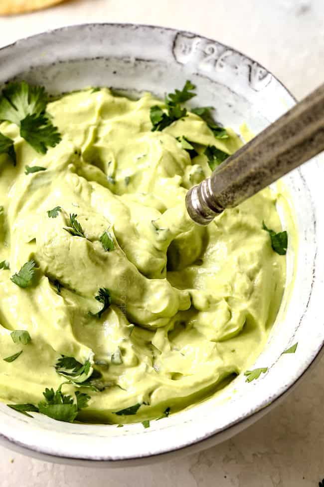 a bowl of avocado crema in a white bowl to top fish tacos 