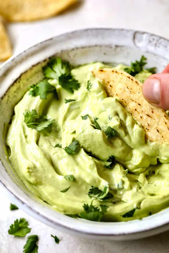 dipping a chip into avocado cream with mayo