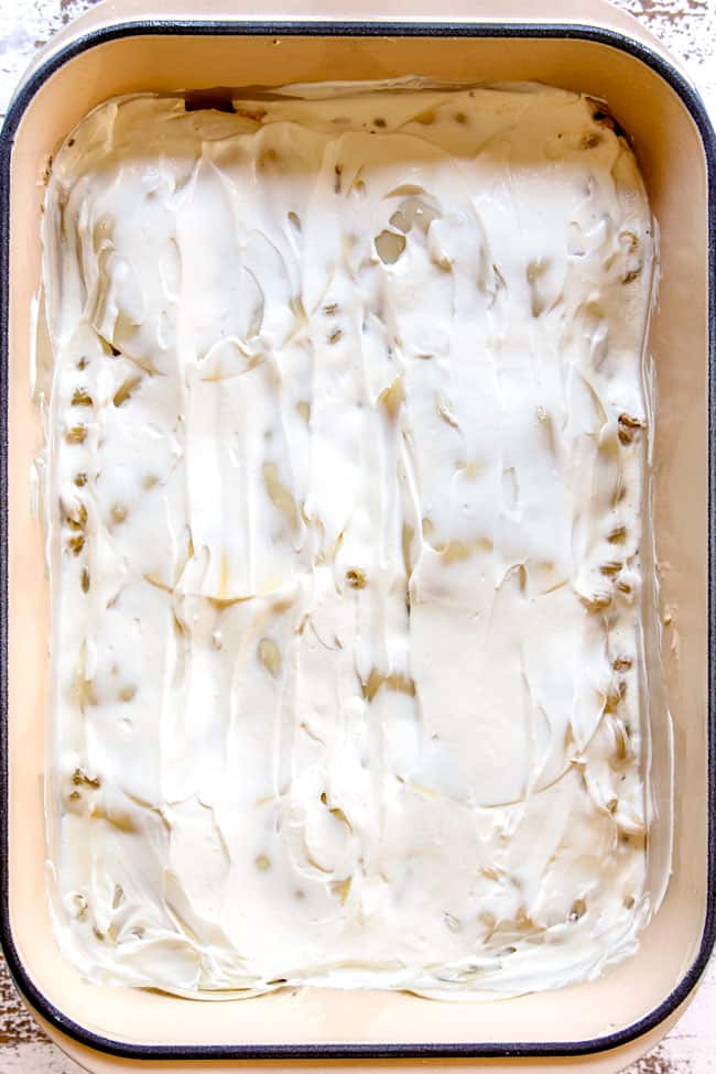 showing how to make Chicken Alfredo Bake by adding a layer of sour cream over pasta