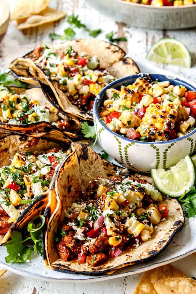 side view of authentic pork taco recipe with topings of corn salsa, cotija chese and avocado crema