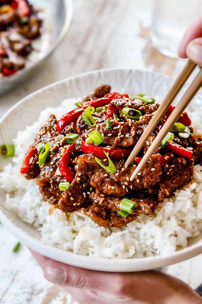 two hands holding a bowl of Szechuan Beef recipe