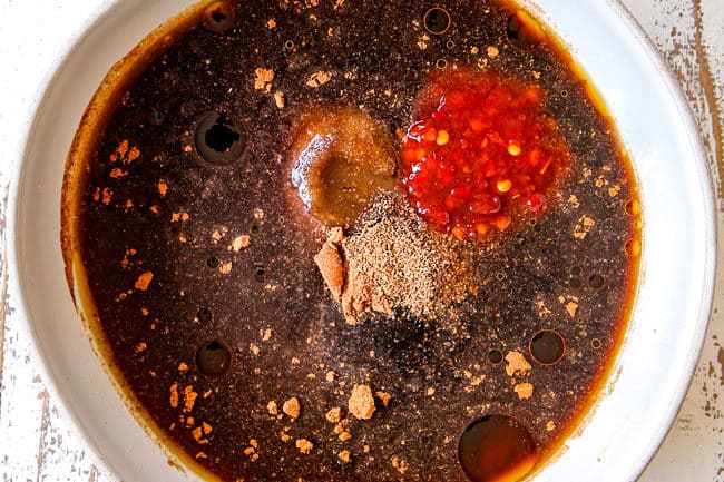 showing how to make Chinese Pepper Steak by whisking the stir fry sauce ingredients together In a white bowl: soy sauce, oyster sauce, chinese 5 spice,  chicken broth, brown sugar 