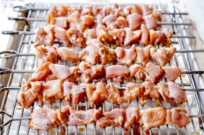 showing how to make yakitori by lining chicken skewers on a cooking rack to bake