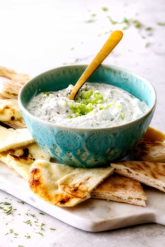 showing how to serve Tzatziki sauce with a bowl surrounded by pita bread