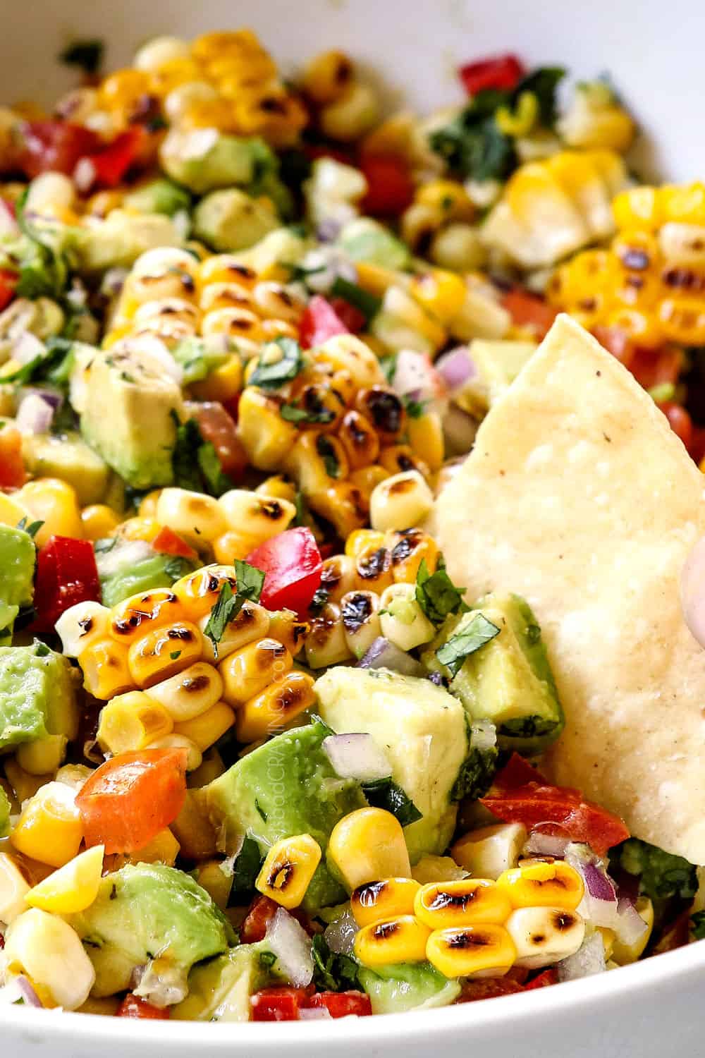 a bowl of easy avocado corn salsa with a chip