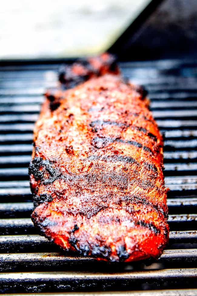 showing how to grill pork tenderloin by placing pork tenderloin on grill