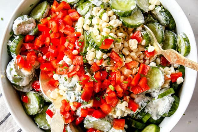 showing how to make cucumber salad by tossing cucumbers and dressing together