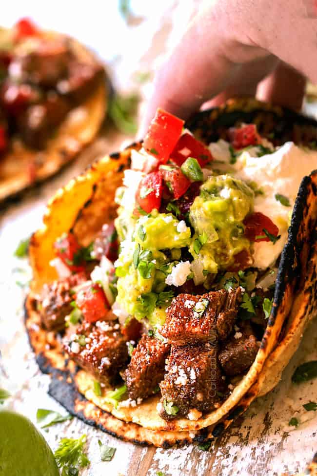 a hand holding a carne asada street taco ready to eat