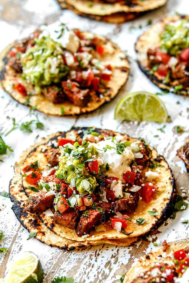 carne asada street tacos laying flat loaded with carne asada, guacamole, pico de gallo